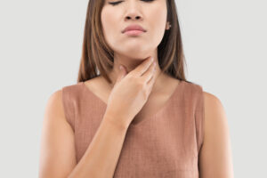 Woman holding her throat and thyroid area