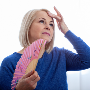 woman fanning herself during hot flash from perimenopause
