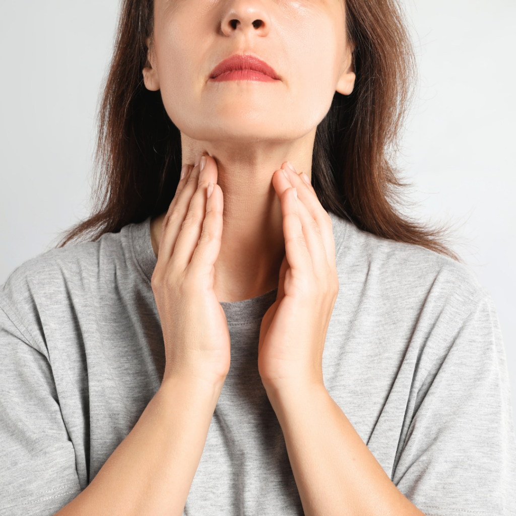 woman touching thyroid on neck